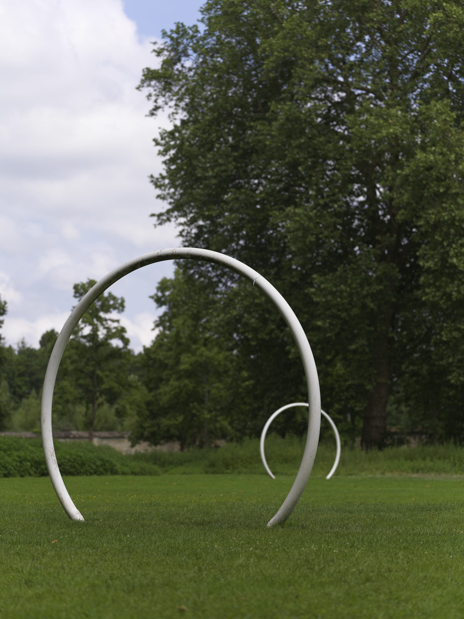 deux grands arcs de cercle blanc disposés dans un jardin