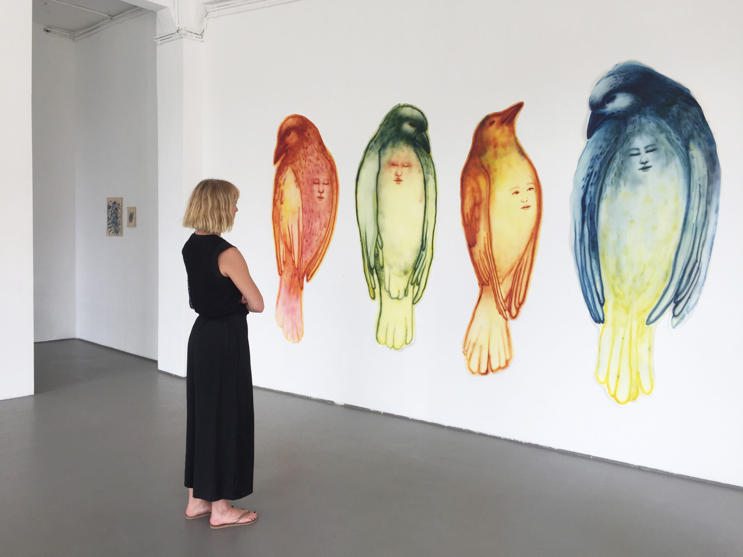 salle d'exposition peintures oiseaux sur papier avec spectateur devant l'oeuvre