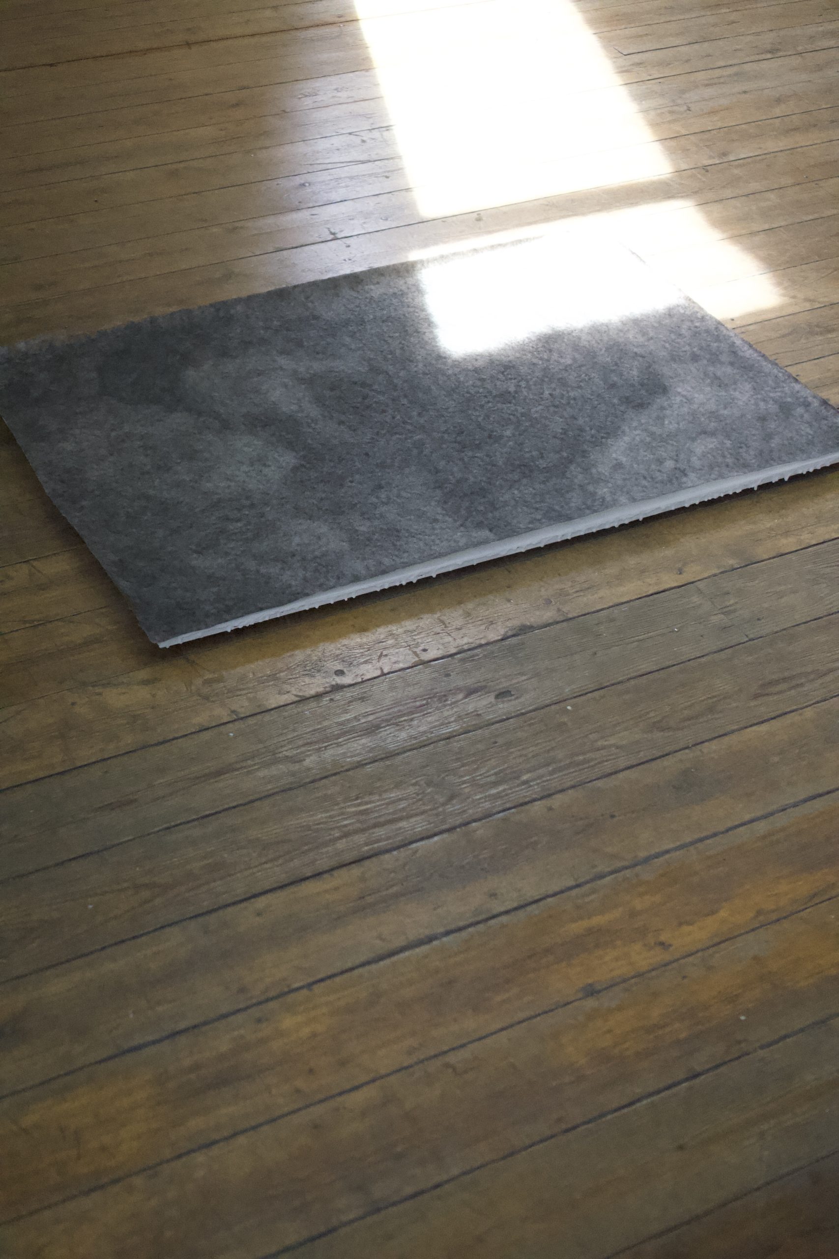 dessin gris posé sur le sol avec une lumière qui le traverse.