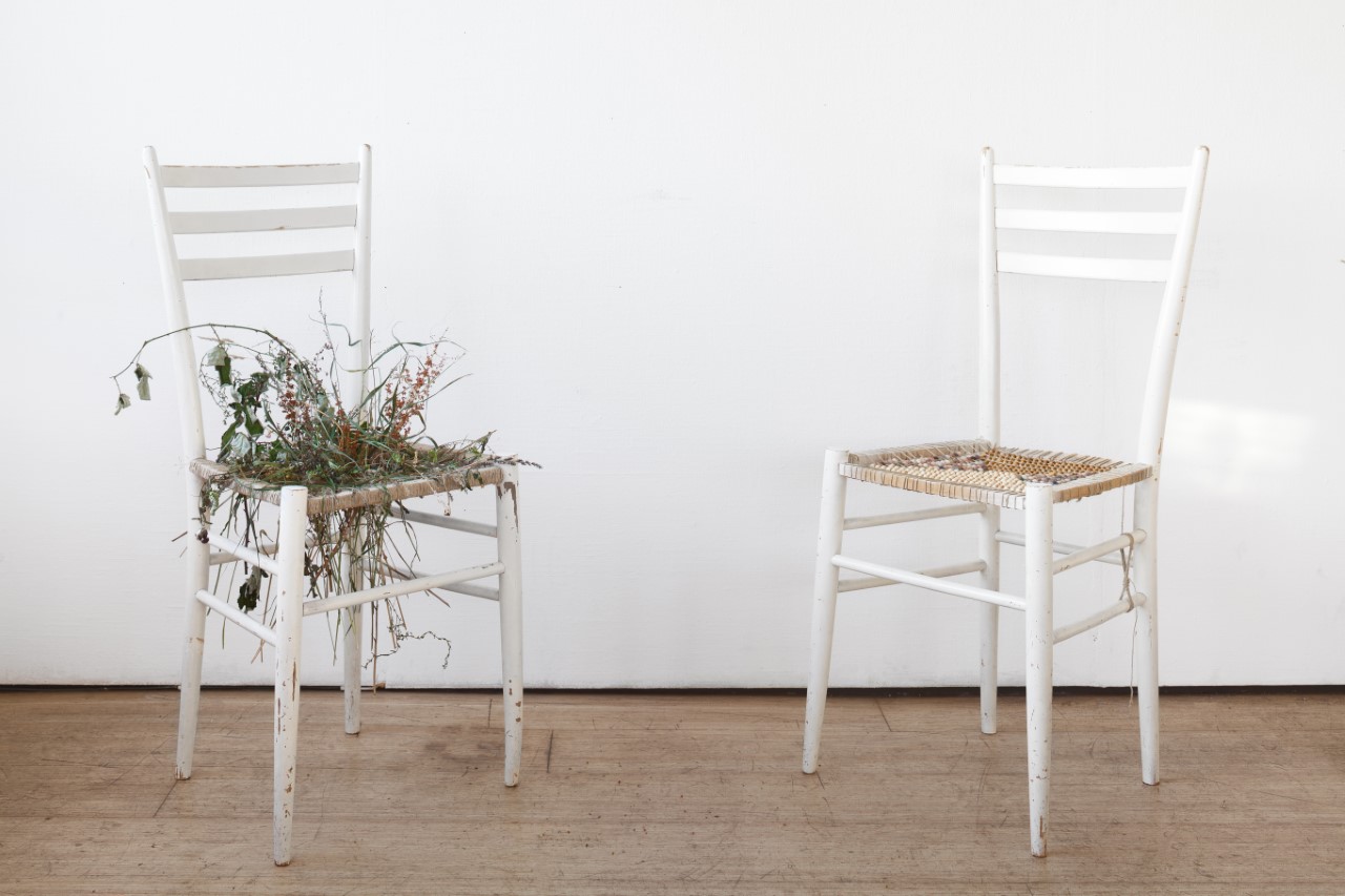 deux chaises blanches dont une avec des fleurs sur le siège.